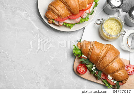 Flat lay composition with tasty croissant sandwich on light grey marble table. Space for text Flat lay composition with tasty croissant sandwich on light grey marble table. Space for text 84757017