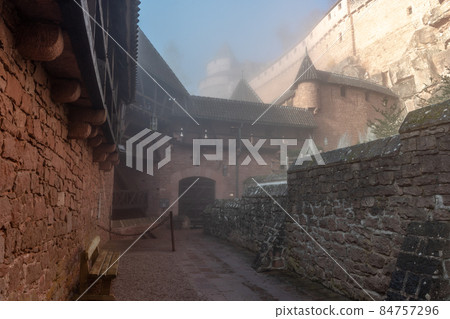 Haut Koenigsbourg fortified castle in the morning mist. Drawbridges, weapons room, keep and cannons, mountain fortress. Alsace, France, Europe. Haut Koenigsbourg fortified castle in the morning mist. Drawbridges, weapons room, keep and cannons, mountain fortress. Alsace, France, Europe. 84757296