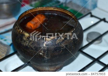 Dark-colored cast iron pot with vegetables. 84757933