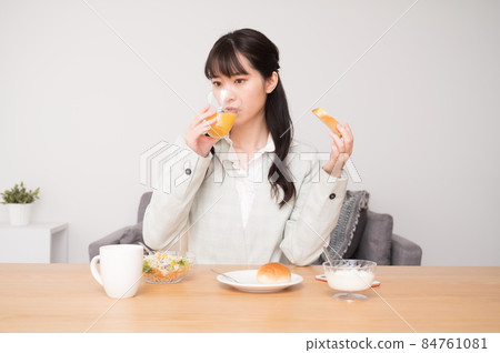 A woman eating breakfast before going to work 84761081