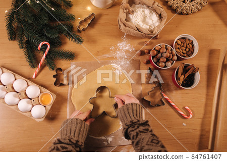 Woman making gingerbread at home. Female cutting cookies of gingerbread dough. Christmas and New Year traditions concept. Christmas bakery. Happy hollidays. First person view Woman making gingerbread at home. Female cutting cookies of gingerbread dough. Christmas and New Year traditions concept. Christmas bakery. Happy hollidays. First person view 84761407