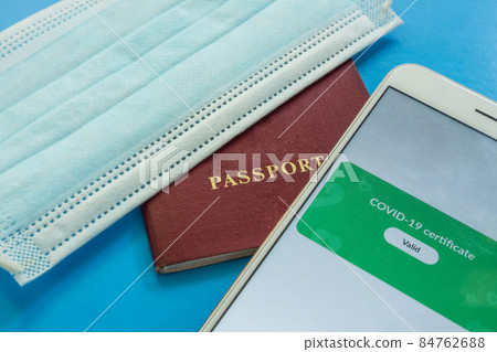 Close-up of a smartphone screen with a valid covid-19 digital vaccination certificate. Next to the passport and medical mask Close-up of a smartphone screen with a valid covid-19 digital vaccination certificate. Next to the passport and medical mask 84762688