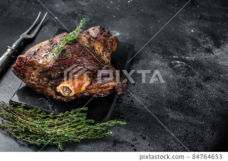 Oven Roasted lamb mutton whole leg with thyme. Black background. Top view. Copy space Oven Roasted lamb mutton whole leg with thyme. Black background. Top view. Copy space 84764653