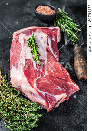Fresh Raw lamb or goat shoulder meat with butcher knife. Black background. Top view Fresh Raw lamb or goat shoulder meat with butcher knife. Black background. Top view 84764983