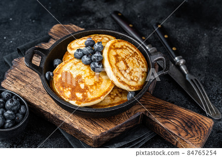 Pancakes with fresh blueberries and maple syrup in a pan. Black background. Top View 84765254