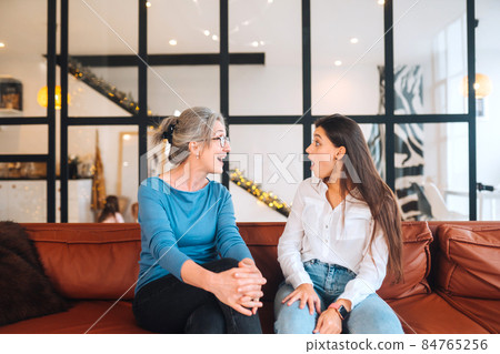 Young woman visiting grandmother at home, women talk Young woman visiting grandmother at home, women talk 84765256