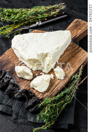Fresh Soft goat cheese on a cutting board with thyme. Black background. Top view Fresh Soft goat cheese on a cutting board with thyme. Black background. Top view 84765257