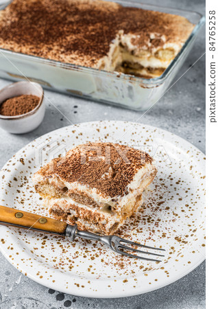 Tiramisu Italian dessert topped with cocoa on a plate. Gray background. Top view Tiramisu Italian dessert topped with cocoa on a plate. Gray background. Top view 84765258