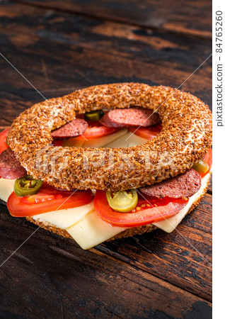 Sandwich with bagel simit, lettuce, tomato, cheese and sausages sucuk. Wooden background. Top view. Copy space Sandwich with bagel simit, lettuce, tomato, cheese and sausages sucuk. Wooden background. Top view. Copy space 84765260