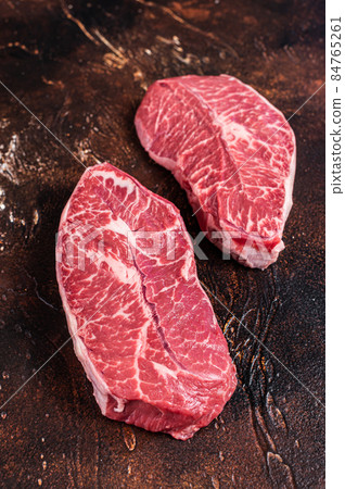 Raw Top Blade or flat iron beef meat steaks on a butcher table. Dark background. Top View Raw Top Blade or flat iron beef meat steaks on a butcher table. Dark background. Top View 84765261
