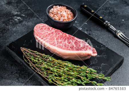 Wagyu raw sirloin steak, kobe beef meat on marble board. Black background. Top view 84765383