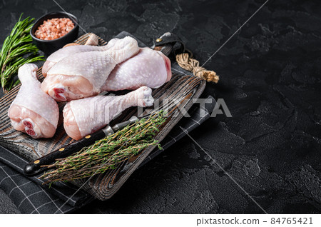 Fresh Raw chicken drumsticks legs on wooden cutting board. Black background. Top view. Copy space Fresh Raw chicken drumsticks legs on wooden cutting board. Black background. Top view. Copy space 84765421