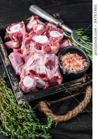 Raw veal beef Oxtail Meat in wooden tray with thyme. Black wooden background. Top view 84765460