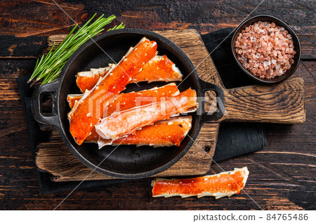 Alaskan King Crab legs Phalanx in a pan with herbs. Dark wooden background. Top view 84765486