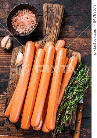 Frankfurter sausages on wooden cutting board. Dark Wooden background. Top view 84765678
