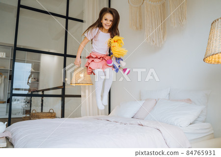 A happy young girl having fun jumping on bed A happy young girl having fun jumping on bed 84765931