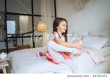 little girl on the bed takes off her shoes little girl on the bed takes off her shoes 84765932