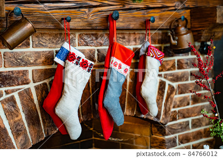 Colorful socks for a gift from Santa Claus hang on the fireplace. Colorful socks for a gift from Santa Claus hang on the fireplace. 84766012