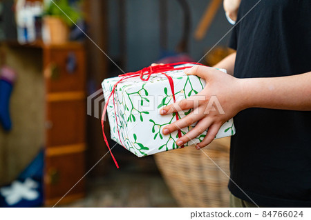 a box with a gift in wrapping paper in hands. a box with a gift in wrapping paper in hands. 84766024
