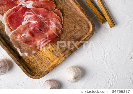 Dry cured Prosciutto crudo parma ham, on white stone table background, top view flat lay, with copy space for text Dry cured Prosciutto crudo parma ham, on white stone table background, top view flat lay, with copy space for text 84766287