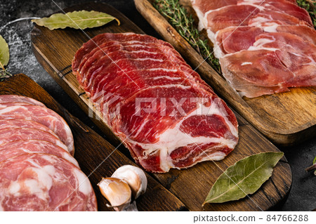 Different meat snacks coppa, prosciutto, on black dark stone table background 84766288