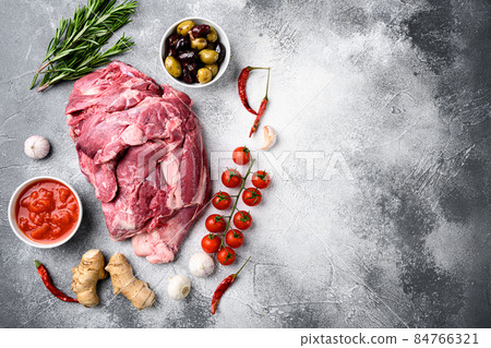Raw lamb shoulder meat ready for baking, with ingredients and herbs, on gray stone table background, top view flat lay, with copy space for text Raw lamb shoulder meat ready for baking, with ingredients and herbs, on gray stone table background, top view flat lay, with copy space for text 84766321