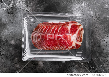 Cured meat coppa pack, on black dark stone table background, top view flat lay, with copy space for text 84766325