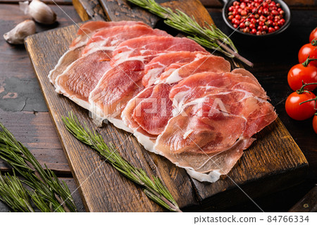 Dry cured Prosciutto crudo parma ham, on old dark wooden table background 84766334