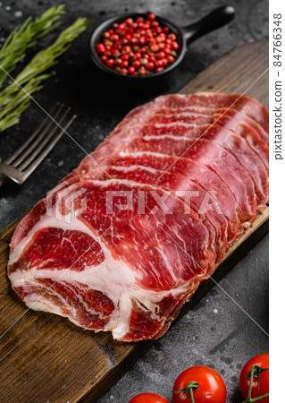 Sliced cured coppa ham, on black dark stone table background 84766348