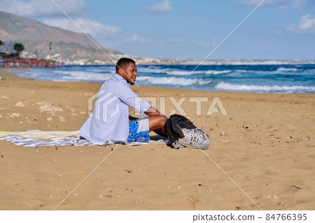 Young positive male tourist sitting resting on the beach 84766395