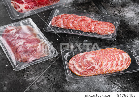 Vacuum packed sausage Prosciutto salami, on black dark stone table background Vacuum packed sausage Prosciutto salami, on black dark stone table background 84766493