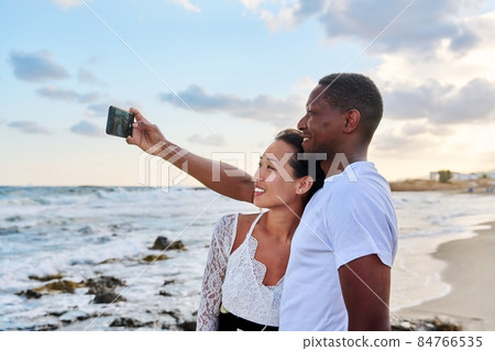 Happy couple in love taking selfie together on smartphone, on beach Happy couple in love taking selfie together on smartphone, on beach 84766535