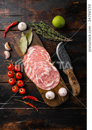 Sliced smoked sausage, on old dark wooden table background, top view flat lay Sliced smoked sausage, on old dark wooden table background, top view flat lay 84766559