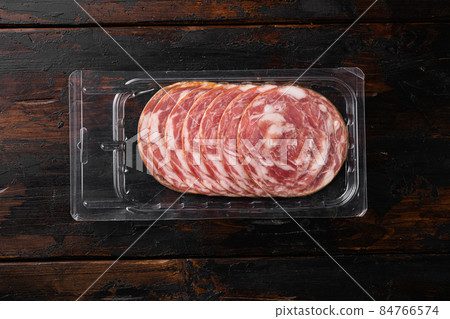 Jamon Serrano traditional Spanish cuisine cured pork meat pack, on old dark wooden table background, top view flat lay, with copy space for text 84766574