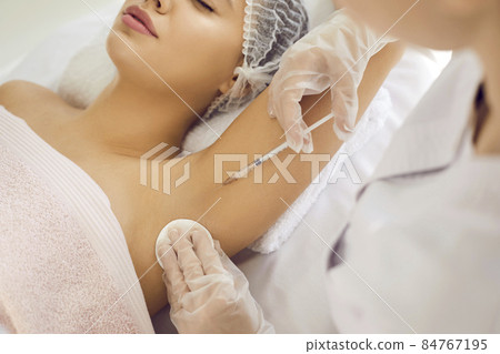 Doctor gives injection in underarm area to reduce armpit sweating, treat hyperhidrosis, prevent bad smell and body odor. Professional injecting glutathione to whiten skin color hyperpigmentation 84767195