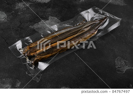 Grilled lamprey vacuum pack, on black dark stone table background, with copy space for text 84767497
