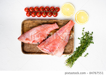Red perch fish meat, on wooden serving board, on white stone table background, top view flat lay Red perch fish meat, on wooden serving board, on white stone table background, top view flat lay 84767551
