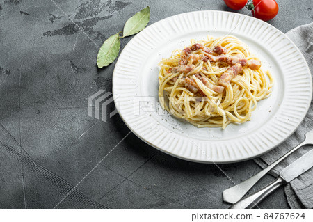 Carbonara pasta. Spaghetti with pancetta, egg, parmesan cheese, on gray stone background, with copy space for text Carbonara pasta. Spaghetti with pancetta, egg, parmesan cheese, on gray stone background, with copy space for text 84767624