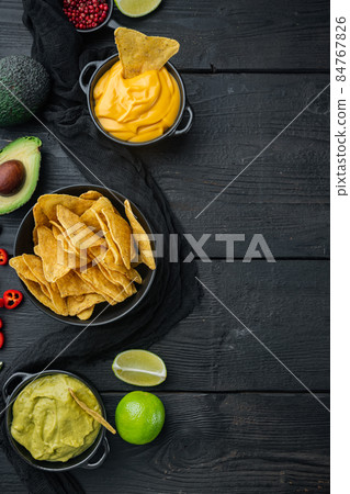 Mexican food concept. Nachos - yellow corn totopos chips with various sauces, on black wooden background, top view or flat lay with copy space for text Mexican food concept. Nachos - yellow corn totopos chips with various sauces, on black wooden background, top view or flat lay with copy space for text 84767826