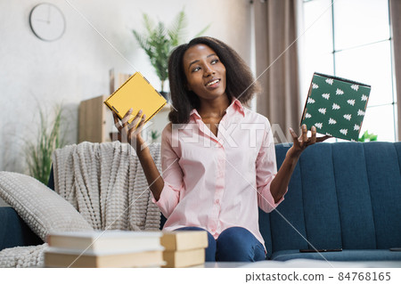 Pleasant woman sitting on couch with gift boxes in hands 84768165