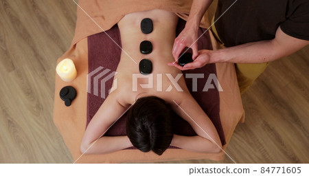 Top view of young and beautiful woman gets hot stone massage therapy in the spa salon. Healthy lifestyle and body care concept. 84771605
