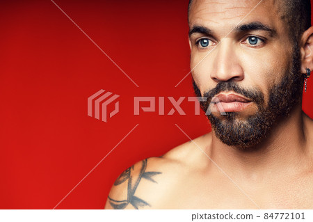 Face with a beard and an earring in the ear of a Cuban man close-up. Studio portrait of a brutal man 84772101