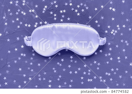 Color of the year 2022 very peri. Trendy colors concept. Satin eye sleeping mask and silver stars confetti on dark black background. Sweet dreams concept. Copy space, flat lay. Accessories for women 84774582