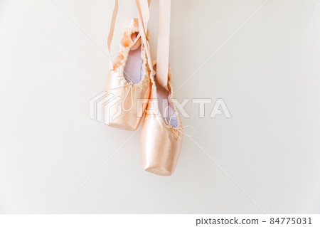 New pastel beige ballet shoes with satin ribbon isolated on white background. Ballerina classical pointe shoes for dance training. Ballet school concept. Copy space 84775031