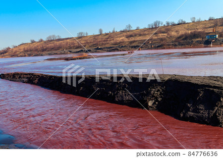 Technical settler of industrial water of mining industry in Kryvyi Rih, Ukraine. Red water polluted with iron ore waste. Discharge of process water in the sump after the iron ore beneficiation Technical settler of industrial water of mining industry in Kryvyi Rih, Ukraine. Red water polluted with iron ore waste. Discharge of process water in the sump after the iron ore beneficiation 84776636