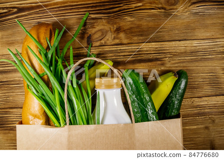 Paper bag with different food on wooden table. Top view. Grocery shopping concept Paper bag with different food on wooden table. Top view. Grocery shopping concept 84776680