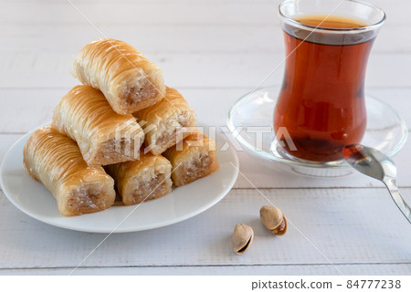 Traditional Turkish pastries Dry dessert baklava, on a wooden surface with Turkish tea and pistachios. Traditional Turkish pastries Dry dessert baklava, on a wooden surface with Turkish tea and pistachios. 84777238