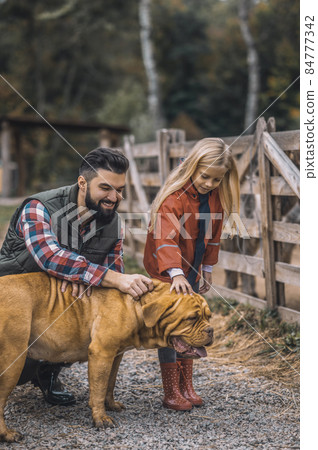 Farmer and his daughter caressing their dog 84777342