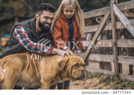 Farmer and his daughter caressing their dog Farmer and his daughter caressing their dog 84777344