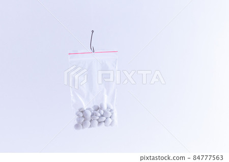White Pills or Tablets Hanging in Small Ziplock Bag on a Fishing Hook White Pills or Tablets Hanging in Small Ziplock Bag on a Fishing Hook 84777563